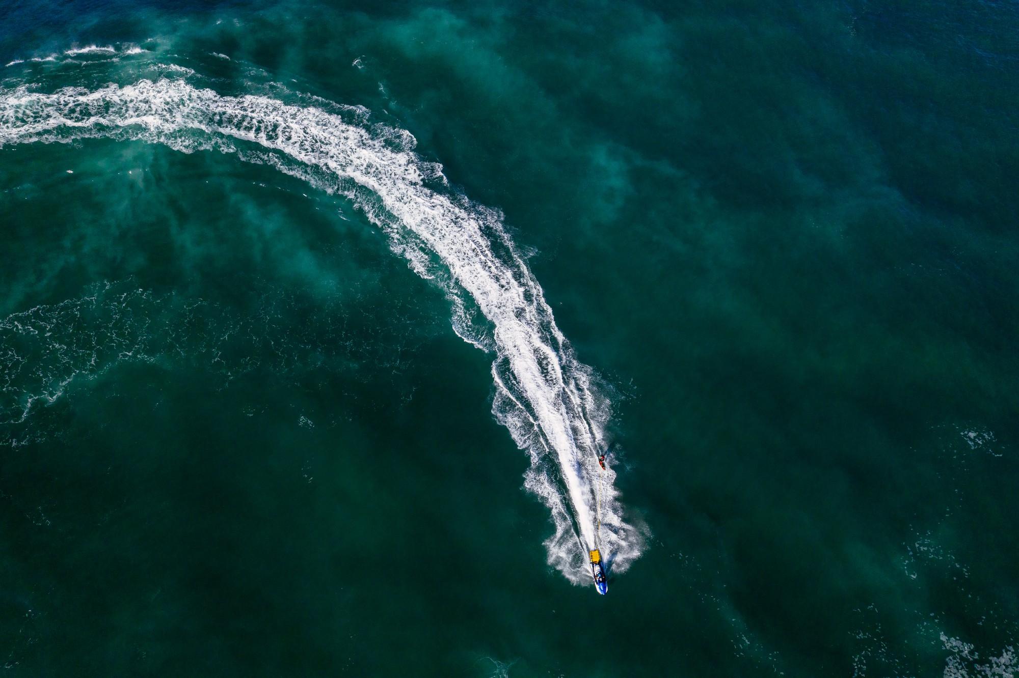 Aerial view of a boat leaving a white wake across open sea